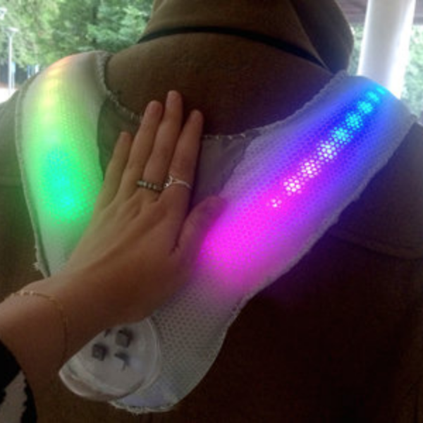 hand on the back of a person wearing a vest with rainbow LED's